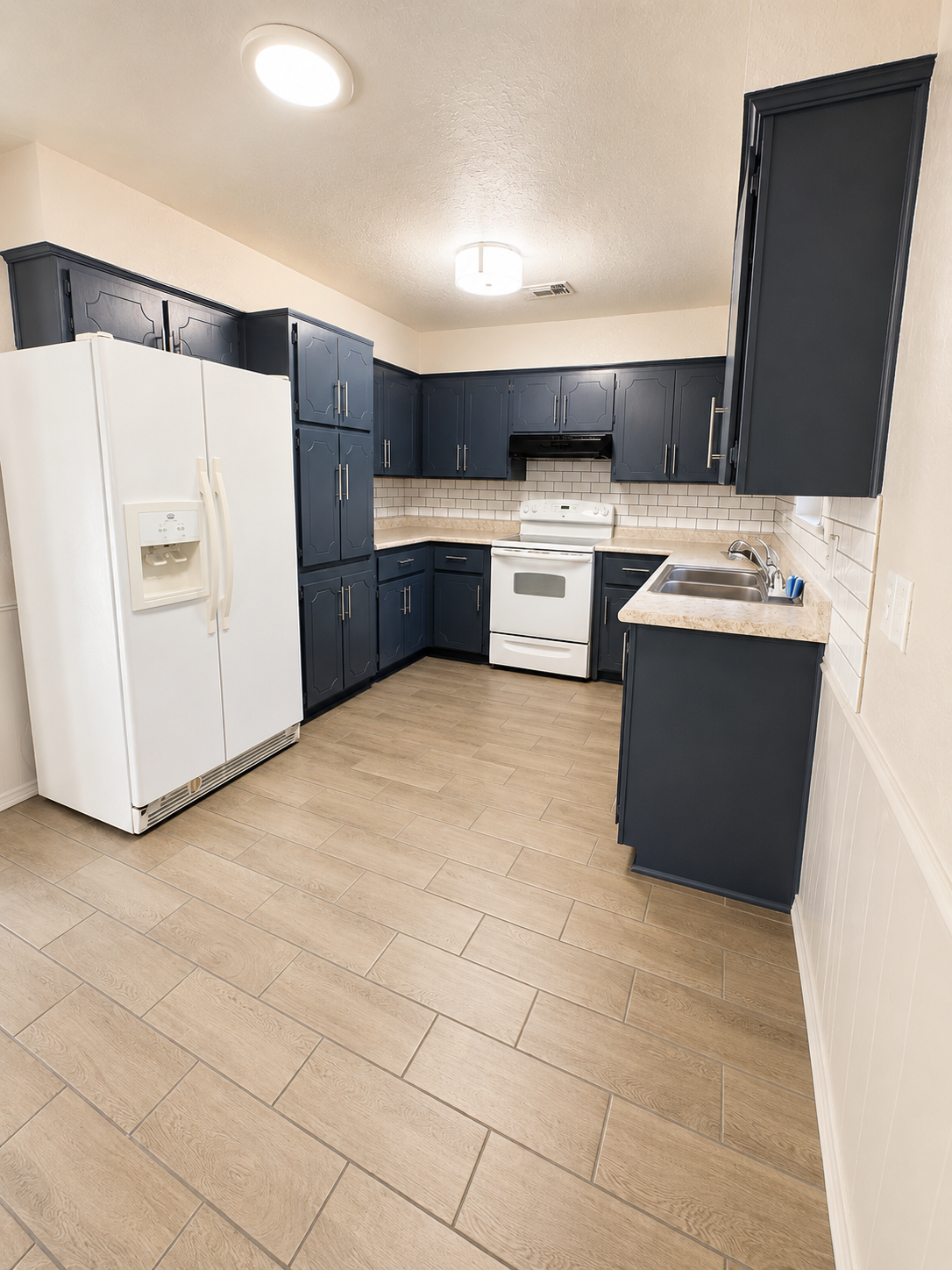 Kitchen with dark cabinetry and white appliances
